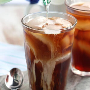 Simply syrup being poured into a glass of cold brew with ice.