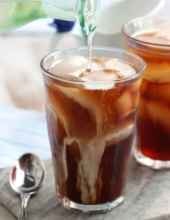 Simply syrup being poured into a glass of cold brew with ice.