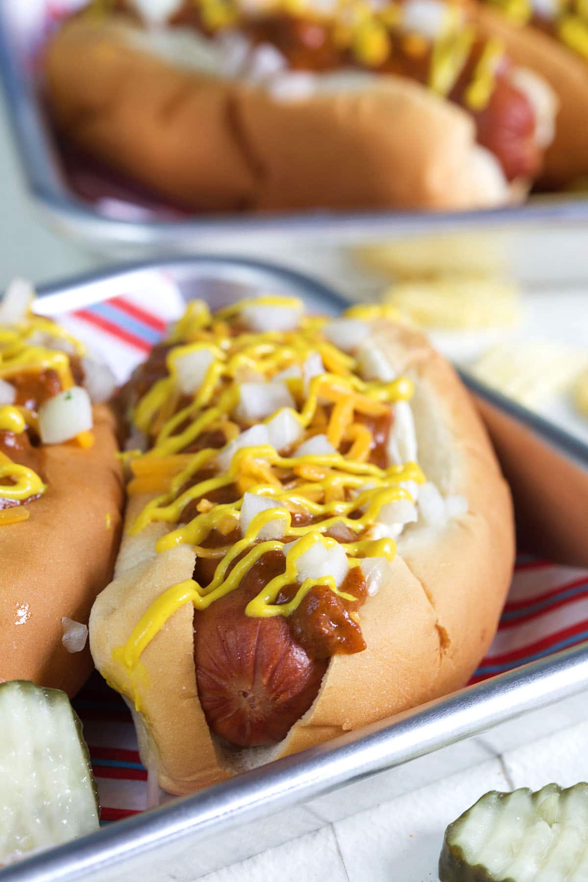 A hot dog is covered with chili, cheese, mustard and onions. 