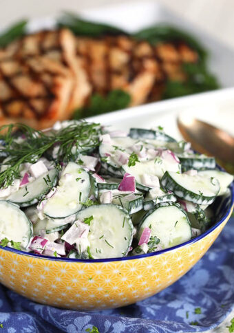 Creamy Cucumber Salad in a yellow bowl on a blue napkin.