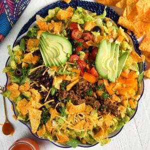 A large bowl is filled to the brim with a Dorito taco salad.