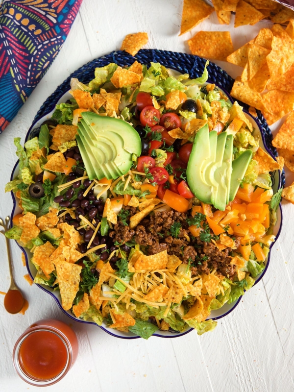 A large bowl is filled to the brim with a Dorito taco salad.