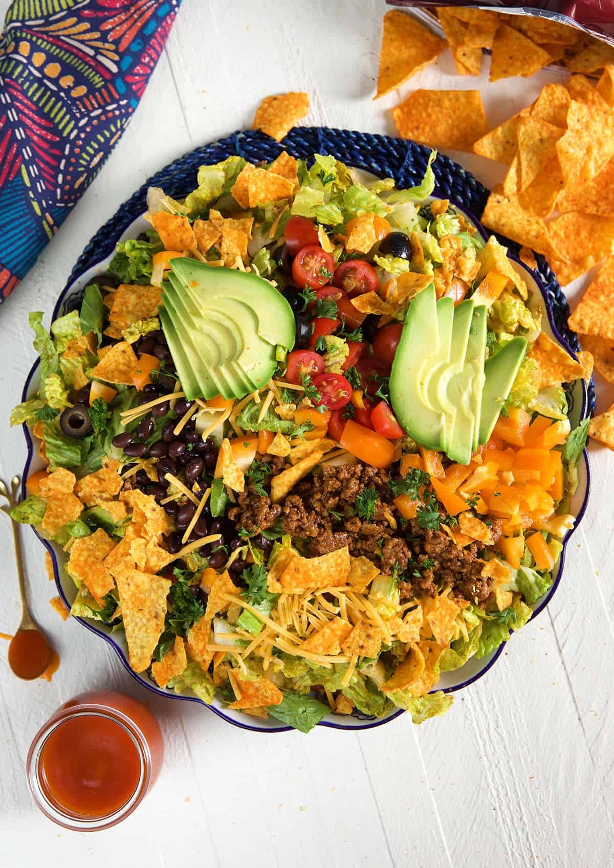 A large bowl is filled to the brim with a Dorito taco salad. 