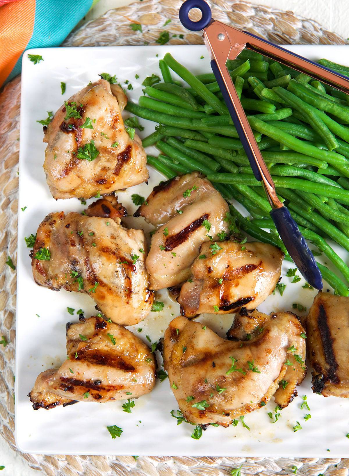 A plate is filled with chicken thighs and green beans. 