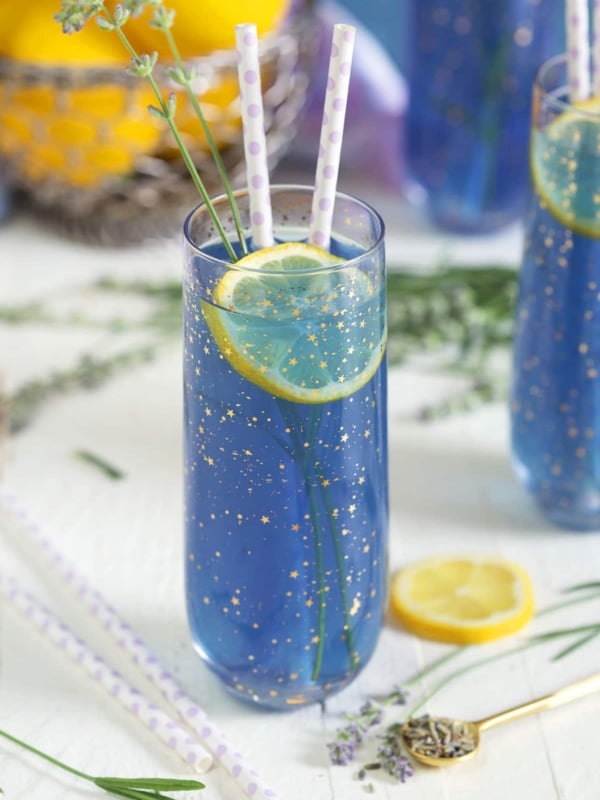 A slice of lemon is in a glass of lavender lemonade.