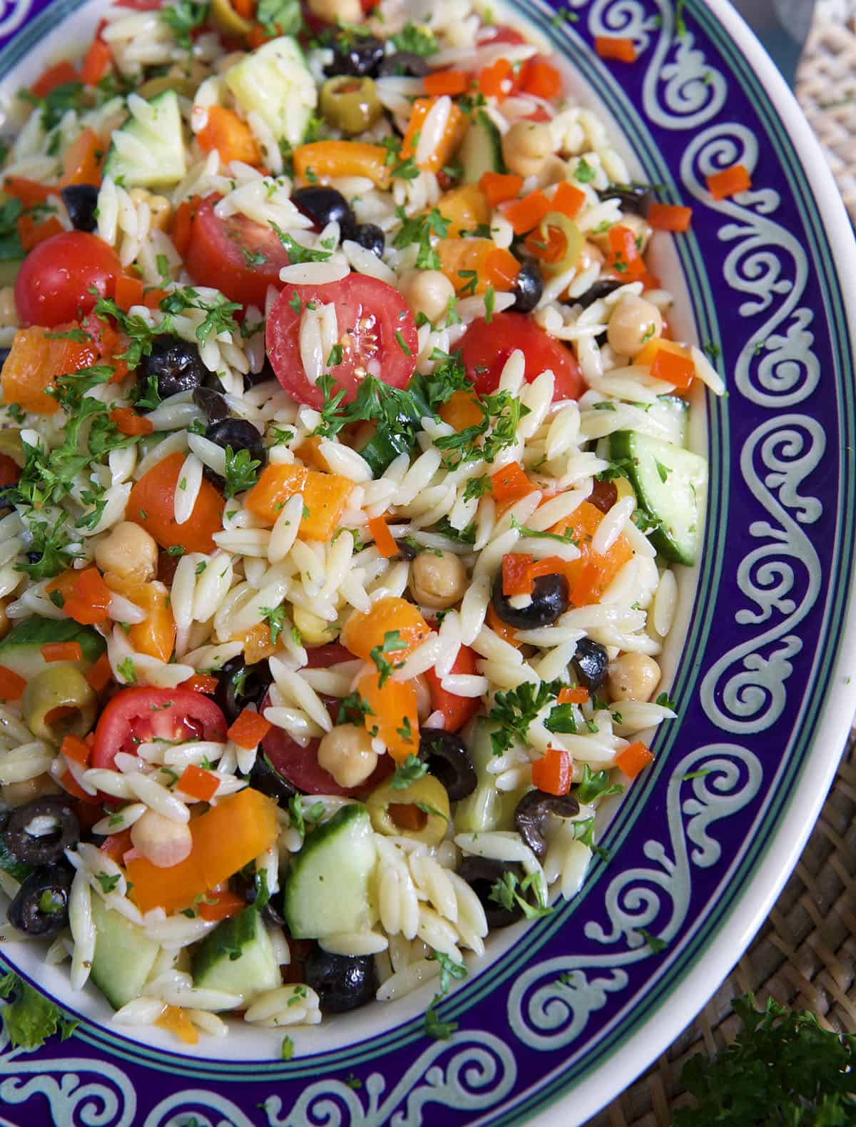 A large ovular bowl is filled with fresh orzo salad. 