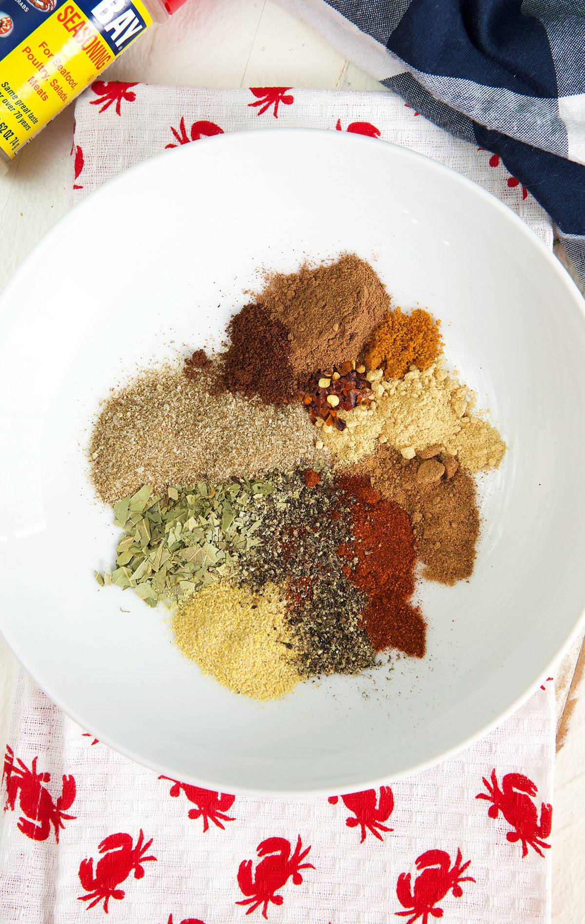 A white bowl contains all of the ingredients for old bay seasoning. 