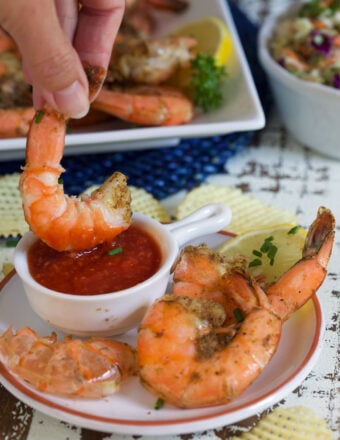 A shrimp is being dipped into red sauce.