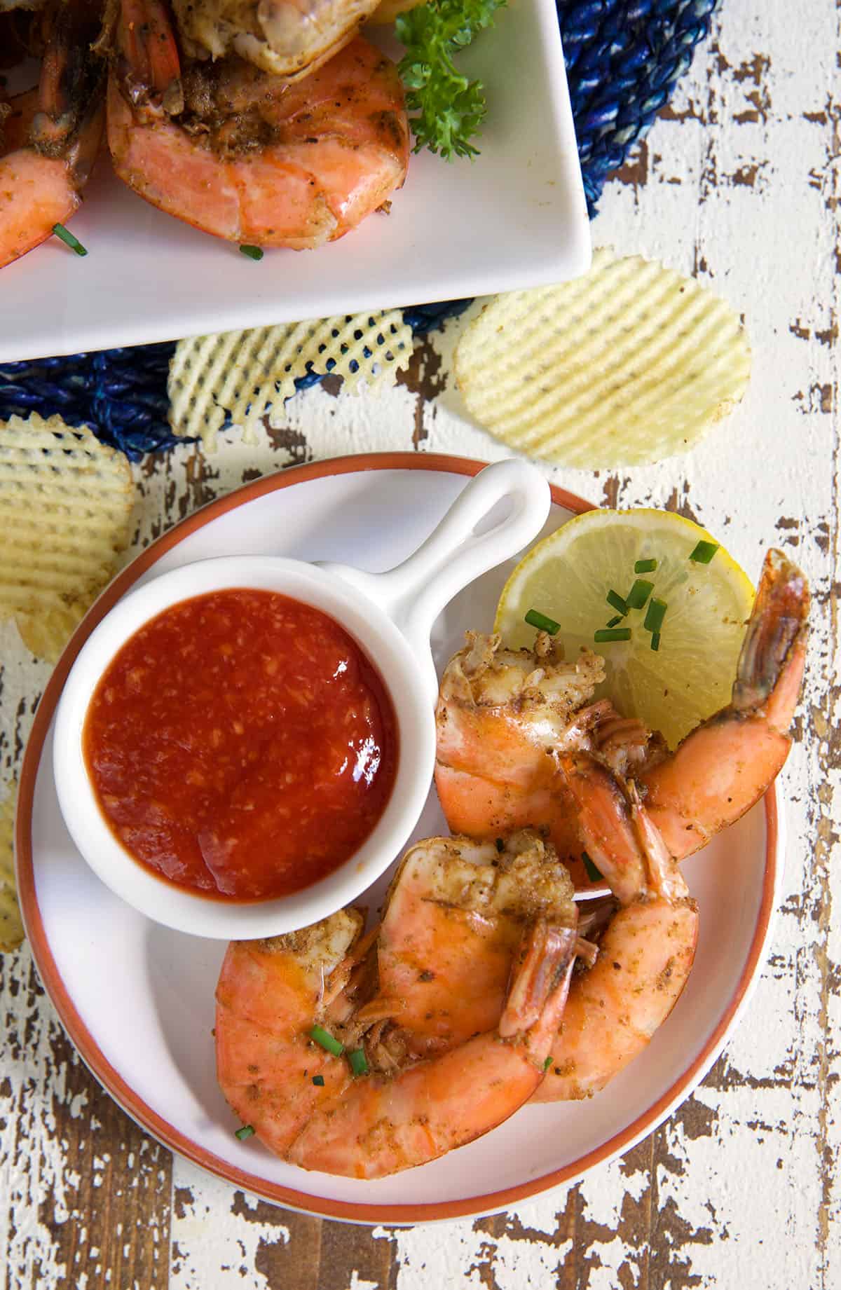 A cup of cocktail sauce is placed next to a serving of shrimp. 