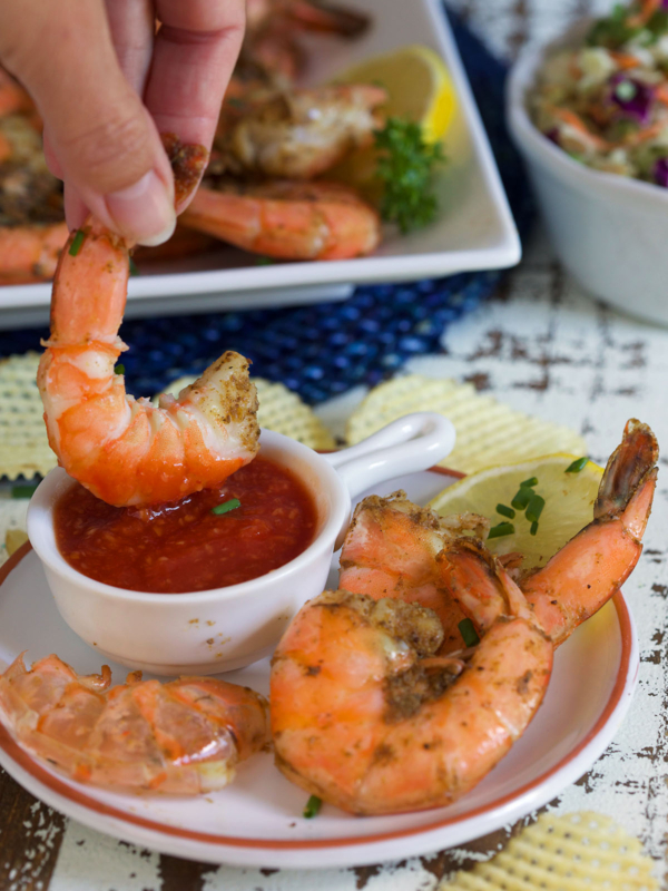 A shrimp is being dipped into red sauce.