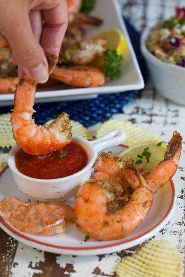 A shrimp is being dipped into red sauce. 