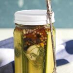 A long fork is placed next to a jar of pickles.