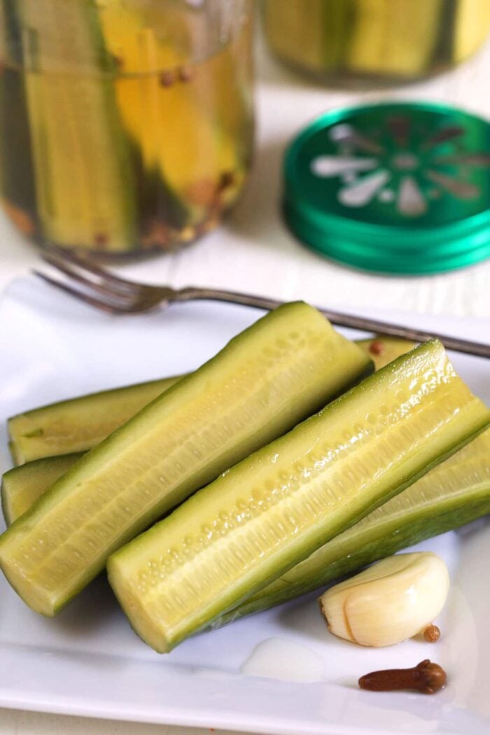 Pickle halves are placed on a white plate.