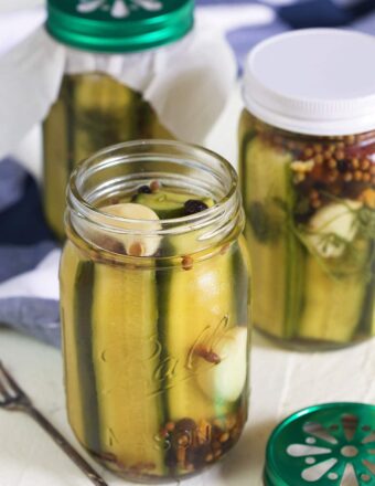 Three jars of pickles are placed on a white surface.