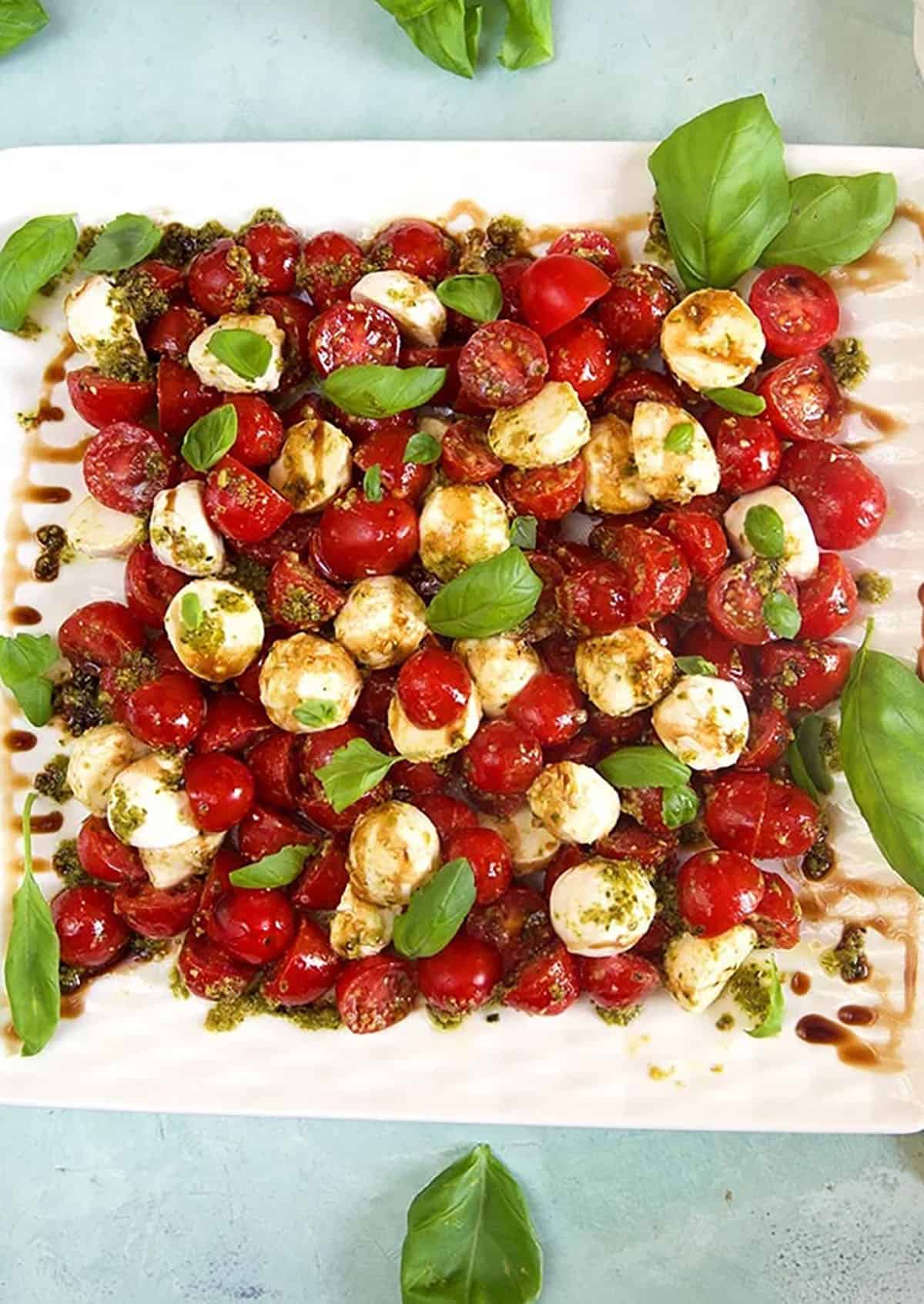 Overhead shot of tomato mozzarella salad on a white platter.
