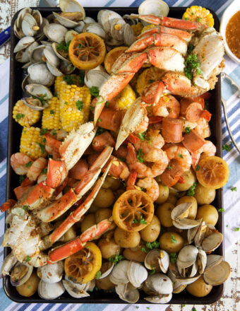 Crab legs, shrimp, clams, corn and potatoes are all boiled and placed on a serving platter.