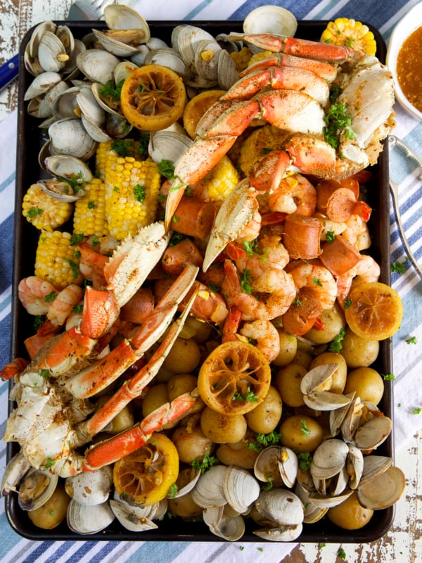 Crab legs, shrimp, clams, corn and potatoes are all boiled and placed on a serving platter.