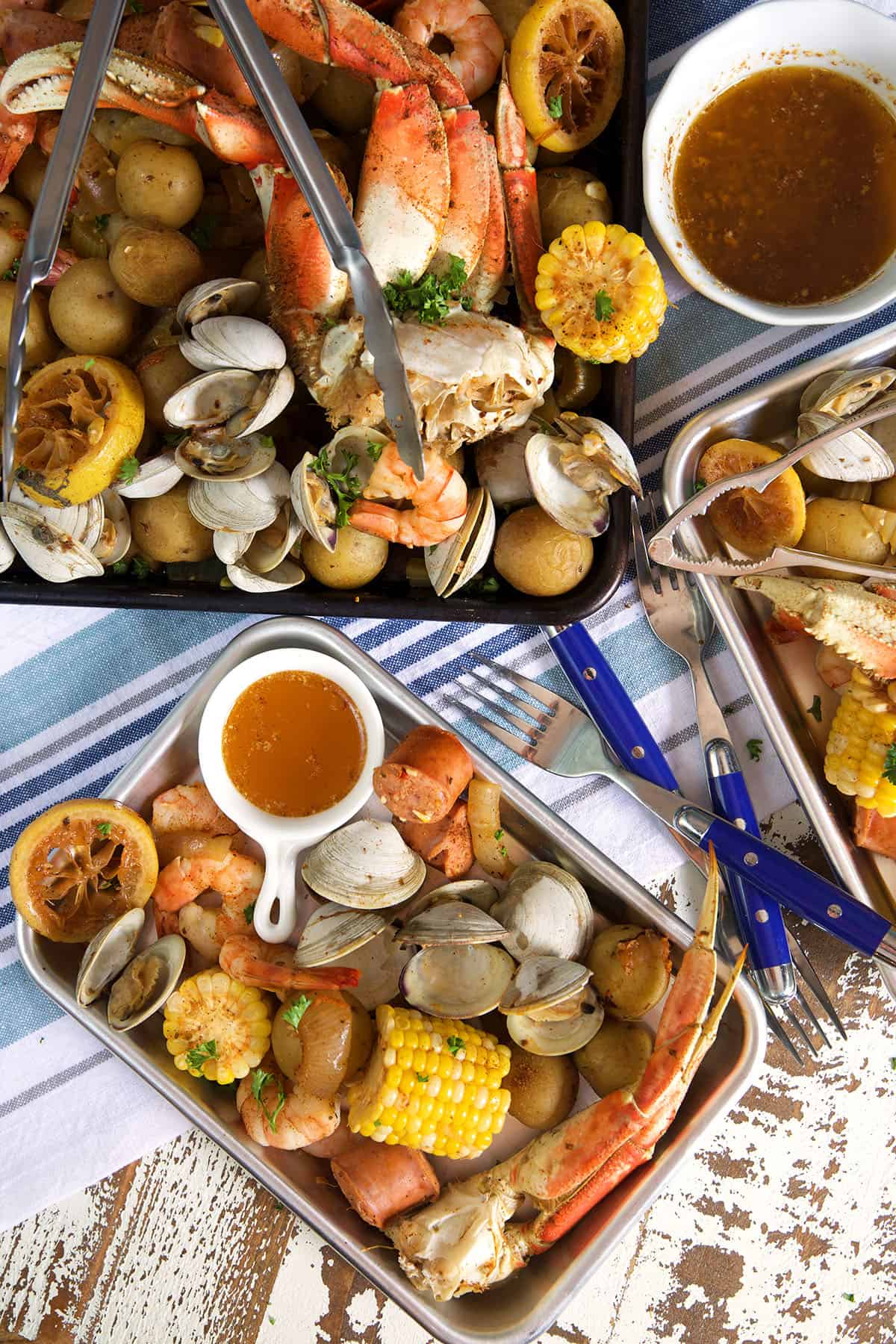 A small rectangular plate is presented with a portion of the seafood boil next to a larger, fuller platter. 