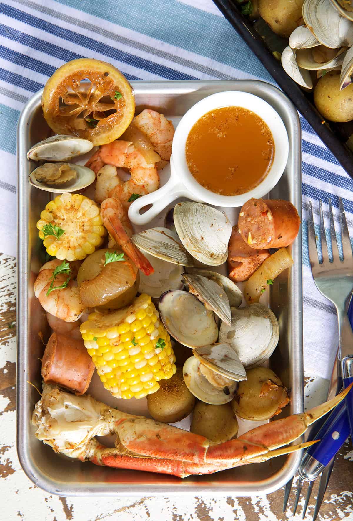 A metal plate is filled with a cajun seafood boil. 