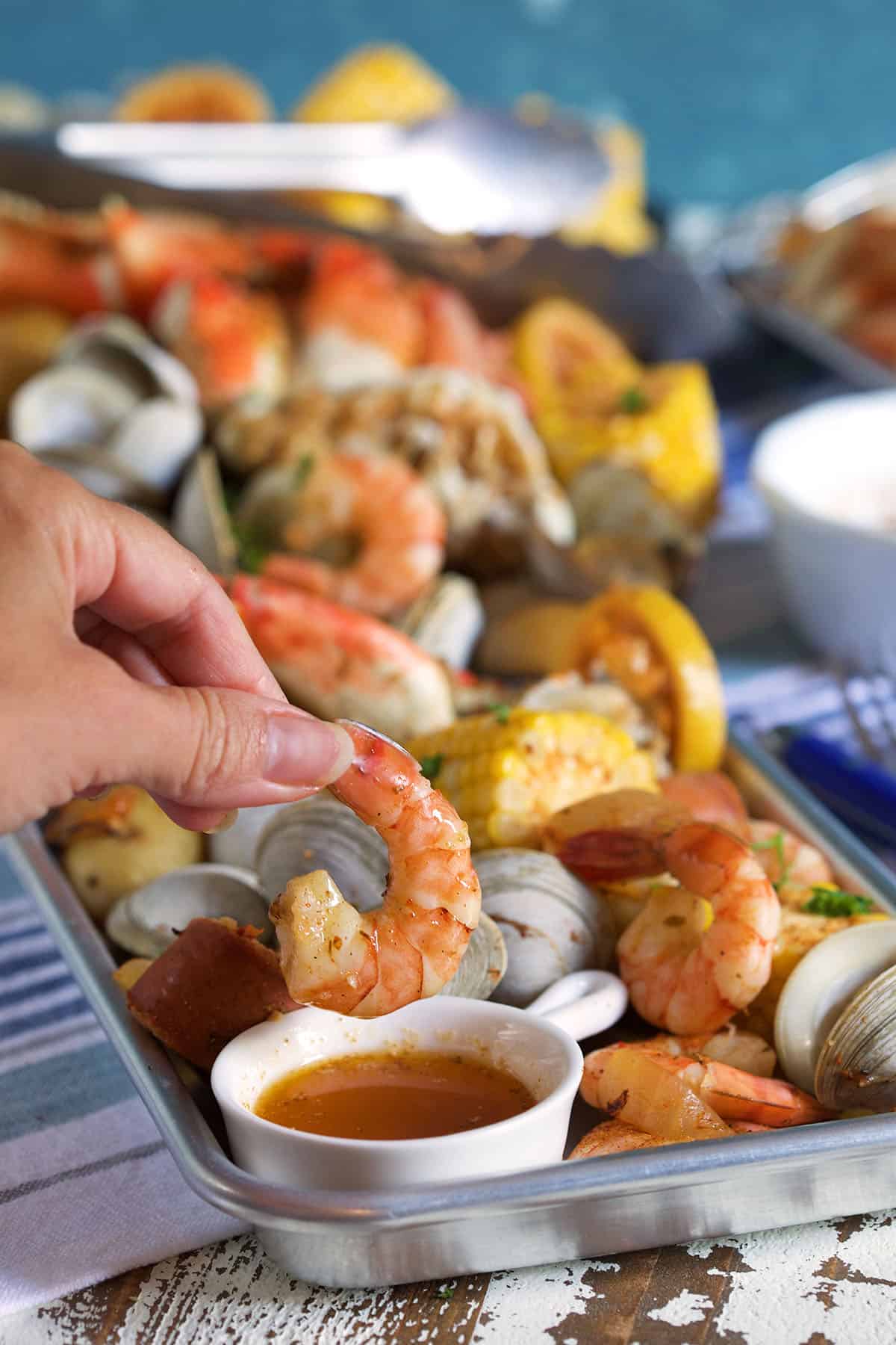 A shrimp is being dipped into a small portion of sauce. 