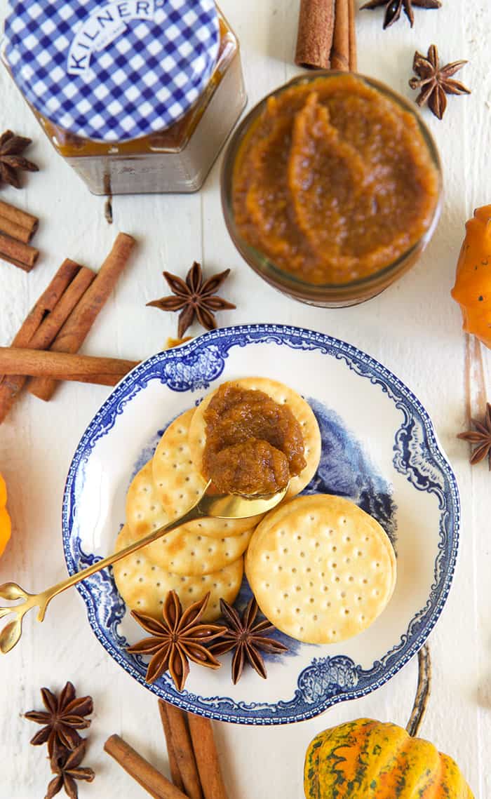 A jar of pumpkin chai butter is placed next to a plate with crackers. 