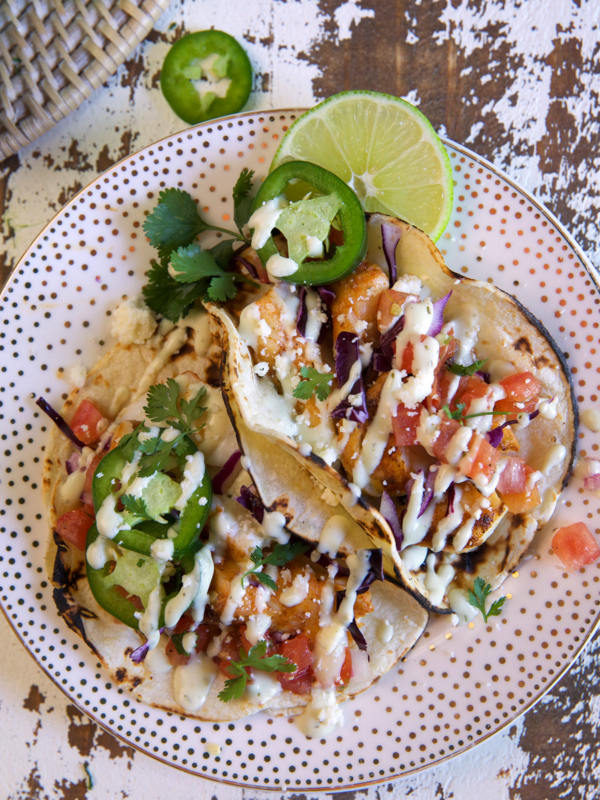 Several cod tacos are on a spotted plate.