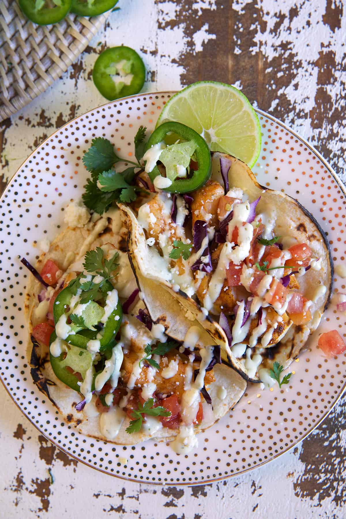 Several cod tacos are on a spotted plate. 