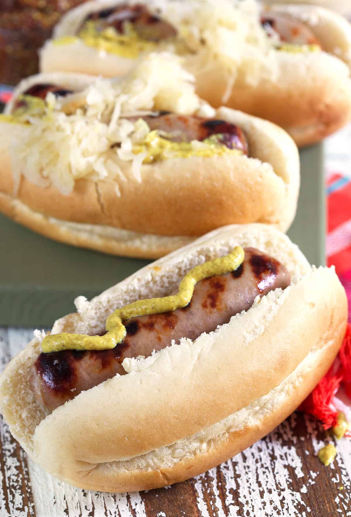 Mustard is drizzled on a beer brat. 
