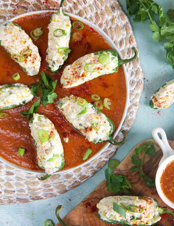 grilled jalapeno poppers in a round dish with roasted red pepper sauce.