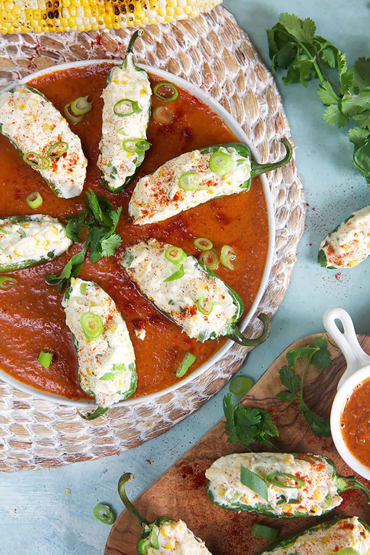 grilled jalapeno poppers in a round dish with roasted red pepper sauce.