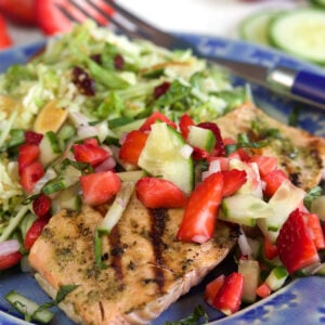 A blue plate is filled with a portion of strawberry salsa and salmon.