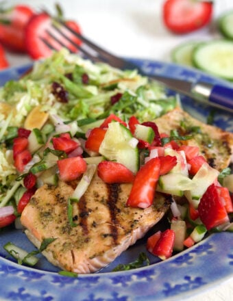 A blue plate is filled with a portion of strawberry salsa and salmon.