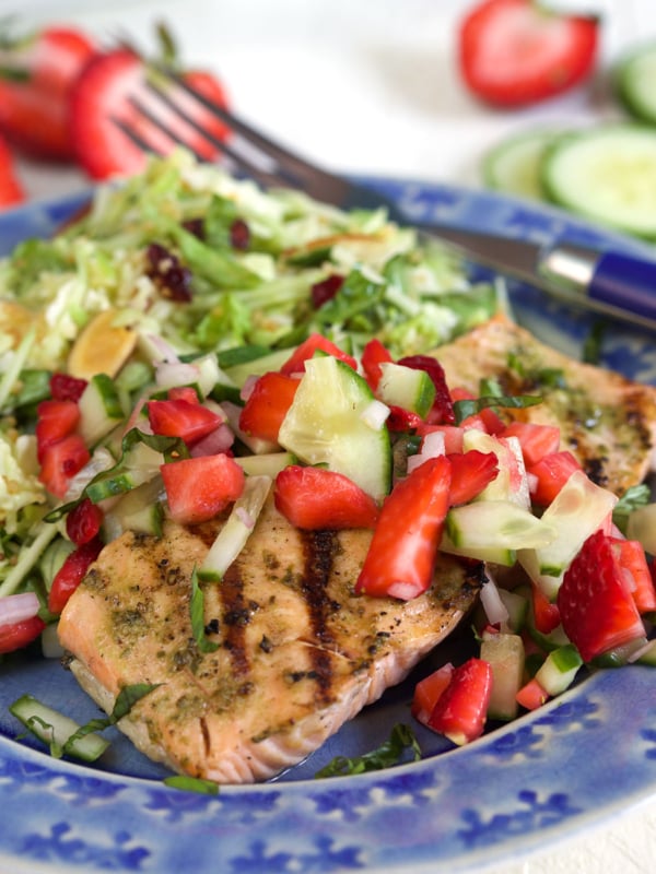A blue plate is filled with a portion of strawberry salsa and salmon.