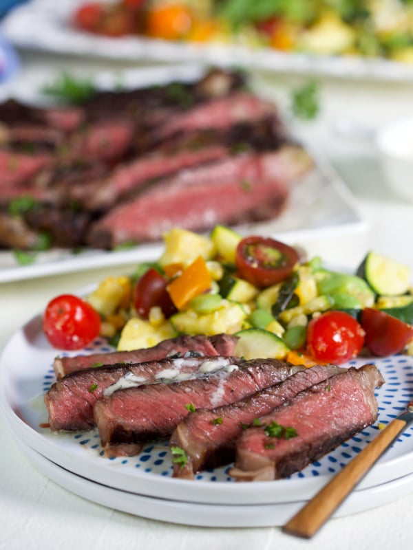 A sliced serving of steak is presented on a blue and white plate.