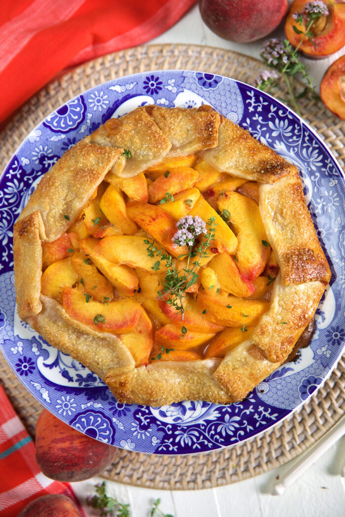A honey thyme peach galette is presented on a blue and white plate. 
