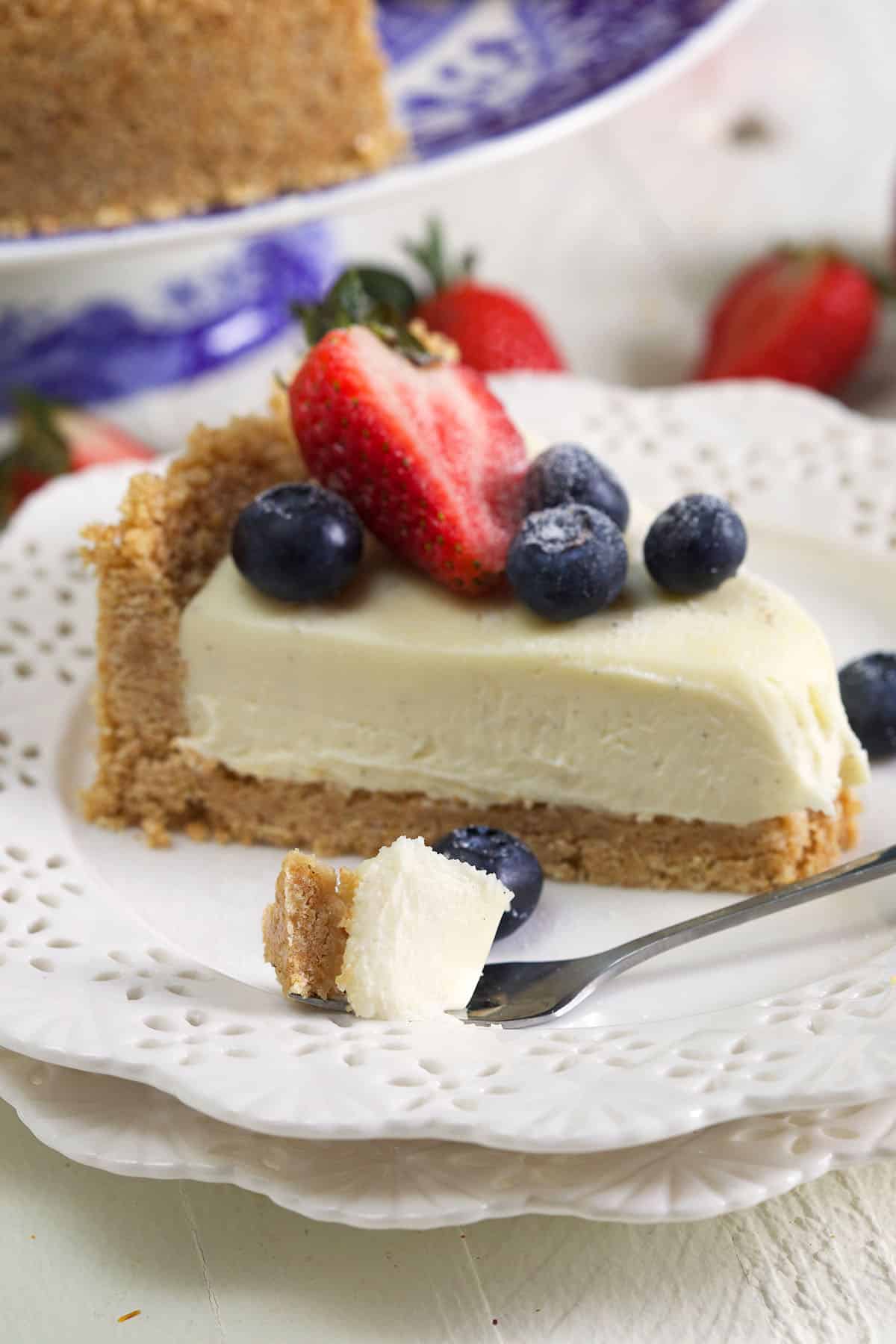 slice of cheesecake on a white plate with a bite on a fork