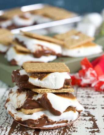 Several baked s'mores are placed next to each other on a wooden surface.