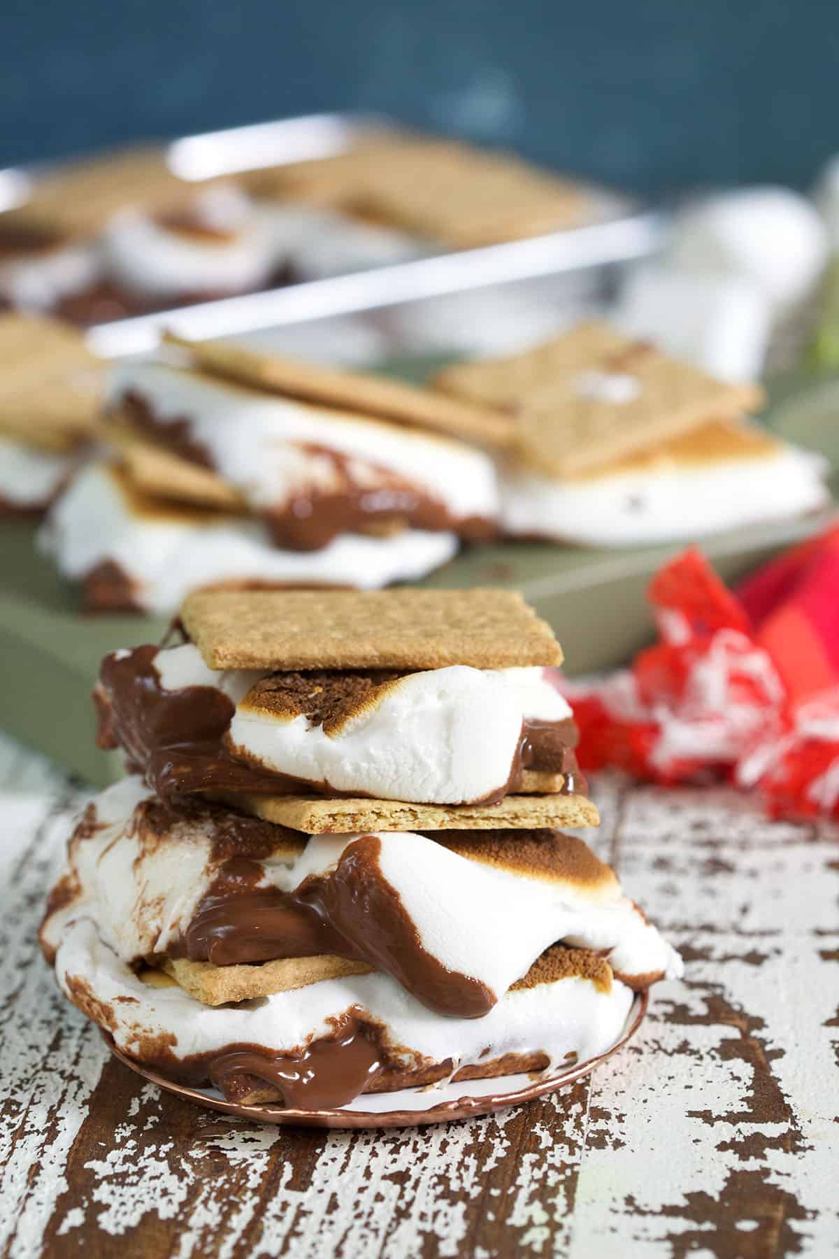 Several baked s'mores are placed next to each other on a wooden surface. 