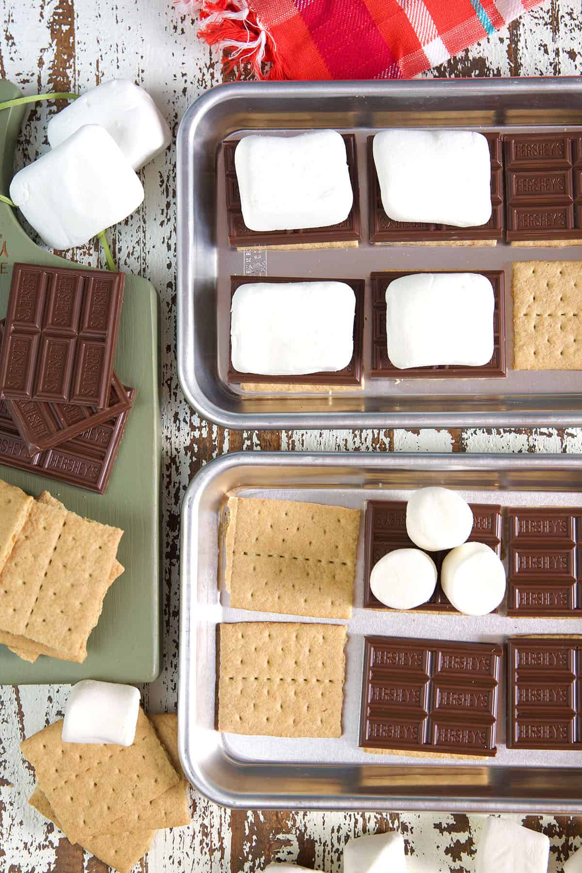 Several graham crackers are topped with marshmallows or various sizes and chocolate. 