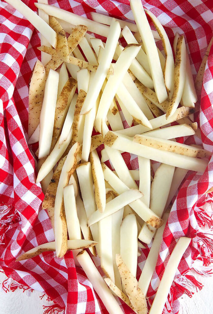 Potatoes cut into fries in a kitchen towel.