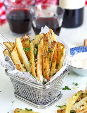 Parmesan Truffle Fries in a wire fry basket with parsley and a glass of wine.