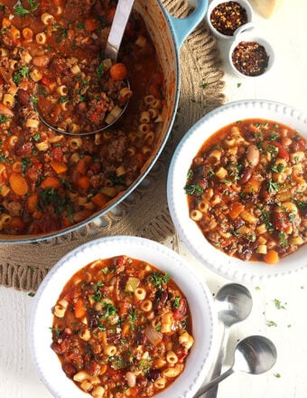 Overhead shot of pasta e fagioli in two white bowls with a blue stock pot.