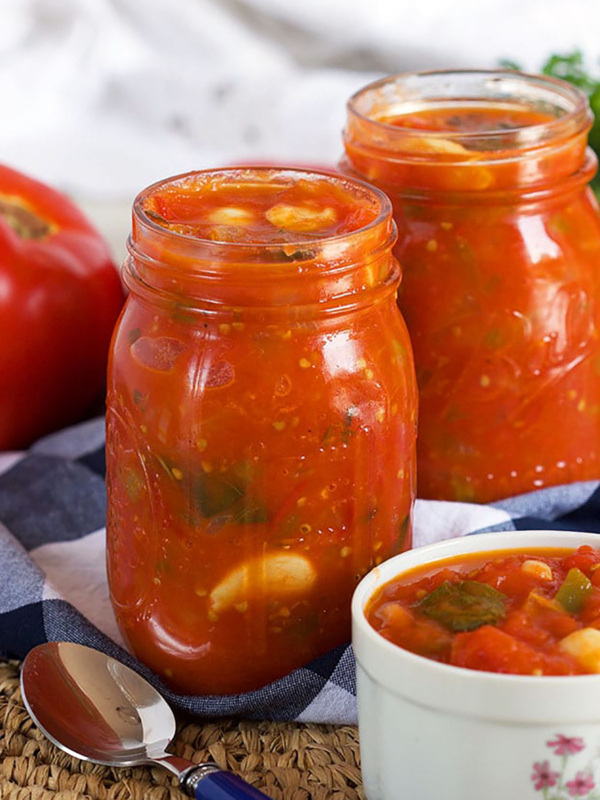 jars filled with stewed tomatoes and a bowl with a portion of stewed tomatoes