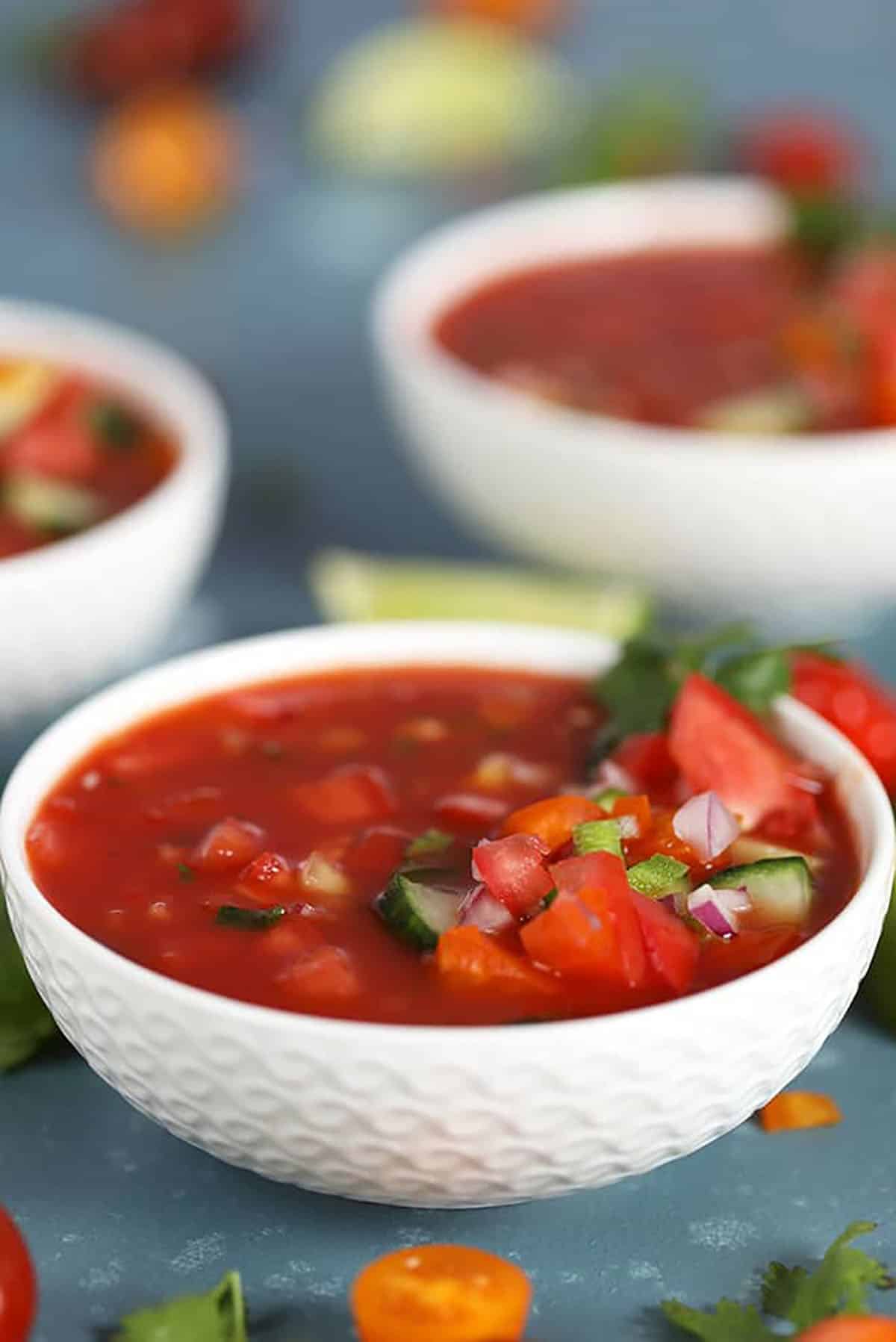 Tomato Gazpacho in a white bowl on a blue background 