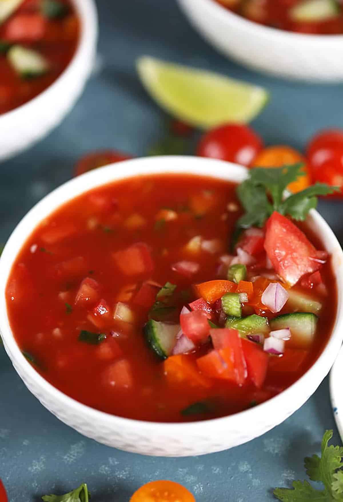 Gazpacho in a white bowl with a blue background