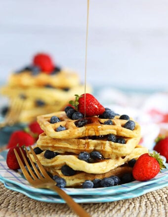 Stack of waffles with berries and syrup being drizzled from thesuburbansoapbox.com