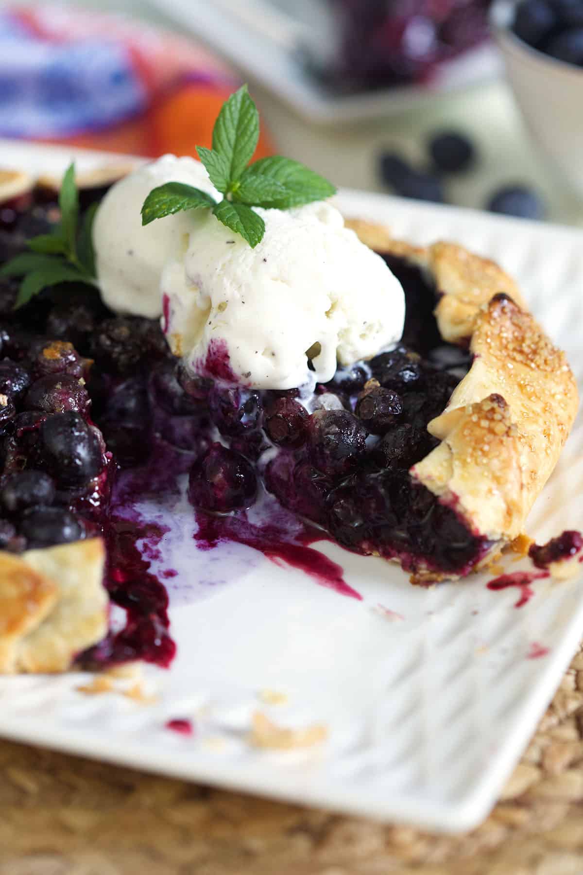 Blueberry Galette with vanilla ice cream on top and a sprig of mint on top.