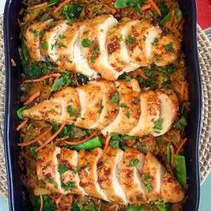 Overhead shot of Baked Teriyaki Chicken Casserole on a bed of rice with veggies in a blue casserole dish.