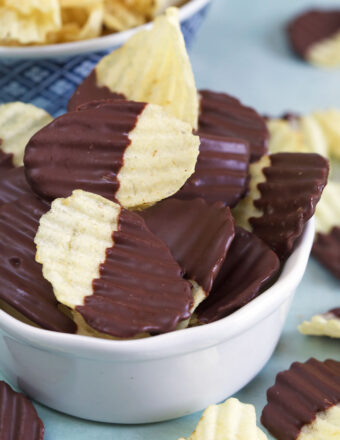 A white bowl is filled to the brim with chocolate covered potato chips.
