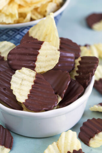 A white bowl is filled to the brim with chocolate covered potato chips.
